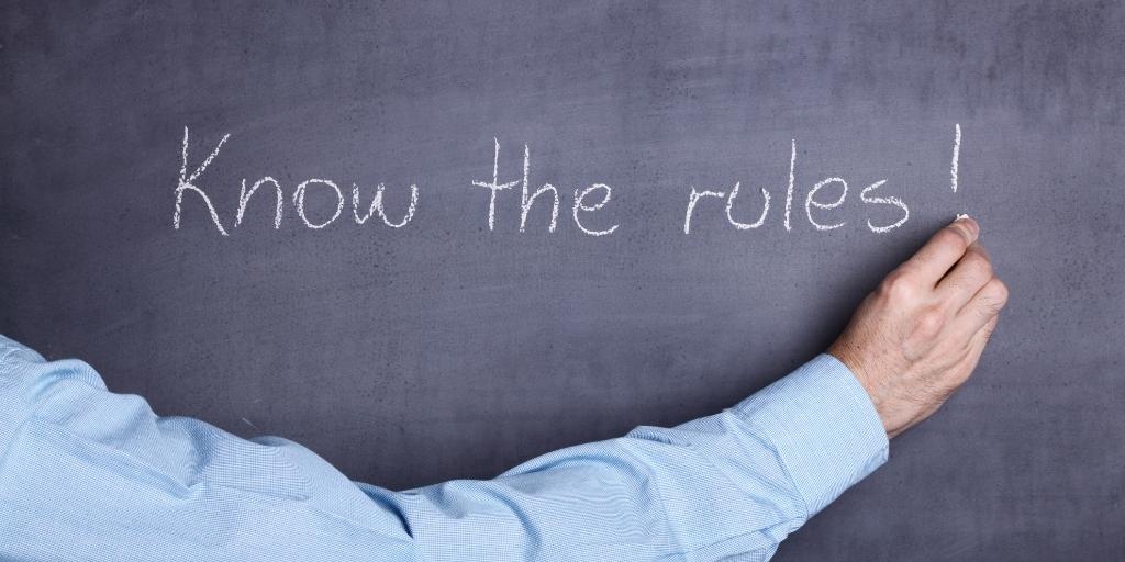 Man writing "Know the rules!" on a chalkboard